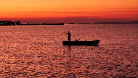 Foto-Panorámica-Retroiluminada-De-Un-Pescador-Al-Atardecer-En-Una-Canoa-En-La-Bahía-De-El-Brete-En-Posadas,-Argentina.