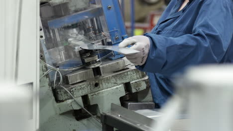 female-worker-wearing-protective-gloves-working-on-a-power-press-machine-inside-a-modern-factory-close-up-low-angle-established