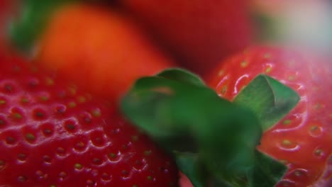 Macro-detailed-video-of-a-pile-of-strawberries,-red-RAW-strawberry,-green-leaf,-on-a-rotating-stand,-smooth-movement,-slow-motion-120fps
