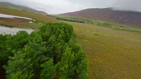 Drone-Volando-Rápido-Y-Bajo-Sobre-Exuberantes-Campos-Verdes-Con-Un-Lago-Y-Ríos