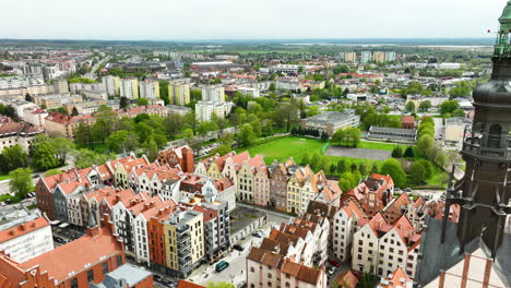 Eine-Luftaufnahme-Des-Majestätischen-Turms-Einer-Kathedrale,-Der-über-Den-Malerischen-Und-Farbenfrohen-Stadthäusern-Einer-Pulsierenden-Stadt-Thront