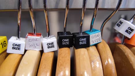 Etiquetas-De-Un-Tamaño-En-Perchas-De-Madera-En-La-Tienda-De-Ropa-De-Moda-En-La-Calle-Principal