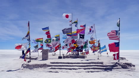 Plaza-of-flags-fluttering-in-breeze-on-vast-Uyuni-Salt-Flat,-Bolivia