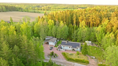 Self-sufficient-house-in-middle-of-sunlit-summer-forest-in-the-Nordics---Aerial-view