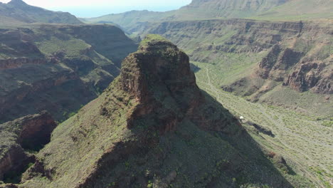 Fantastic-aerial-view-in-orbit-over-the-Titana-rock-on-the-island-of-Gran-Canaria,-seeing-beautiful-mountains-and-near-the-Ansite-fortress