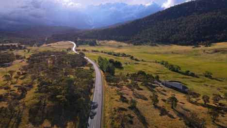 Hermosa-Luz-Del-Sol-En-Una-Casa-Rural-Y-Una-Carretera-Rural-Con-Espectaculares-Nubes-De-Tormenta-Sobre-El-Parque-Nacional-Kosciuszko,-Nsw,-Australia