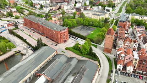 sprawling-view-of-Elbląg,-showcasing-its-urban-blend-of-historical-and-modern-architecture,-verdant-parks-amidst-the-city-layout,-and-the-serpentine-river-Elbląg-carving-through