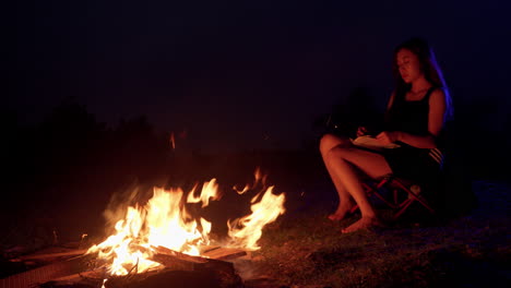 Lagerfeuer-Camping-Asiatische-Junge-Weibliche-Modell-Sitzt-Vor-Dem-Feuer-In-Der-Nacht-Beim-Lesen-Eines-Buches