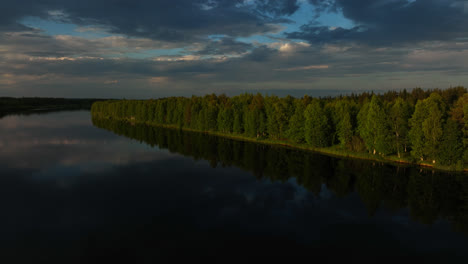 Aerial-view-circling-over-trees-at-a-reflecting-lake-in-summer-evening-in-Lapland