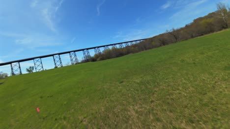 A-low-angle-view-with-an-FPV-drone-flying-towards-the-Moodna-Viaduct-in-Salisbury-Mills,-NY-on-a-sunny-day