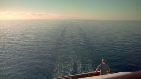 Man-looking-at-the-ocean-on-the-sailing-cruise-ship-sunset-evening