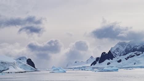 Paisaje-De-Montañas-Antárticas-Al-Atardecer,-Hermoso-Paisaje-Y-Nubes-Dramáticas-Y-Cielo-Con-Picos-Montañosos-E-Icebergs,-Calentamiento-Global-Y-Cambio-Climático-En-La-Península-Antártica-Con-Agua-De-Mar-Oceánica