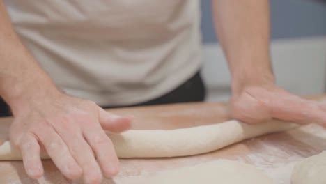 Baker-rolling-baguette-dough,-close-up
