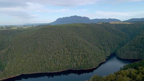 Disparo-De-Drones-Inclinados-De-Un-Denso-Bosque-De-Arbustos-En-El-Lago-Barrington-Con-El-Monte-Roland-En-El-Fondo-Cerca-De-Sheffield,-Tasmania,-Australia