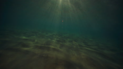 Blendende-Lichtstrahlen-Funkeln-über-Der-Sandigen-Meeresoberfläche