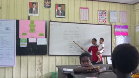 Profesor-Impartiendo-Clases-Con-Un-Bebé-En-La-Mano-Del-Sistema-Escolar-Papú-Indonesio