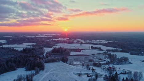 Sunset-over-snowy-landscape,-vibrant-skies,-winter-dusk,-aerial-view