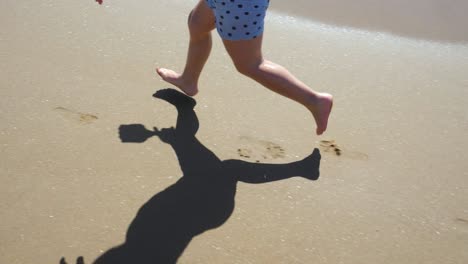 Close-up-of-a-three-year-old-boy's-feet-running-fast-along-the-beach,-shooted-in-slow-motion