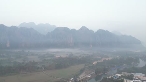 drone-shot-of-foggy-valley-in-Vang-Vieng,-the-adventure-capital-of-Laos