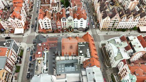 Aerial-view-of-Elbląg's-historical-center-with-its-distinctive-colorful-row-houses-and-terracotta-roofs,-intersecting-streets,-and-parked-cars