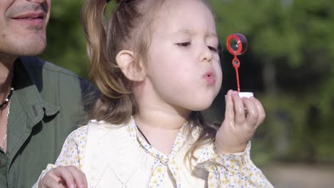 Una-Niña-Alegre-Jugando-Con-Burbujas-Con-Su-Padre-En-El-Parque