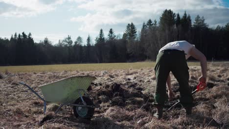Man-Digging-And-Putting-Soil-Into-Wheelbarrow---Wide-Shot