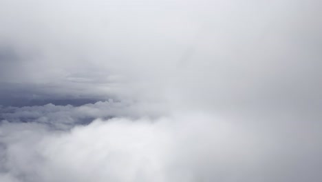 Aerial-shot-above-soft-white-clouds-with-a-glimpse-of-blue-sky-and-distant-horizon