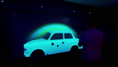 Man-plays-game-with-black-light-car-at-U2-UV-Zoo-Station-Experience,-Vegas