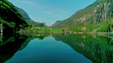 Countryside-town-on-a-fjord-in-Norway---aerial-approach-over-glassy-water