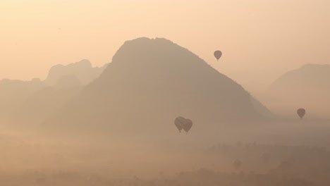 hot-air-balloons-at-sunrise-in-foggy-valley-in-Vang-Vieng,-the-adventure-capital-of-Laos