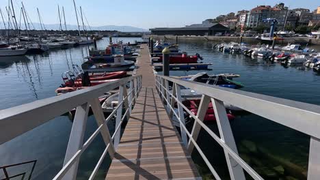 wooden-walkway-in-the-dock-of-the-harbour-with-sea-rescue-boats-in-the-middle-of-the-boats-of-fishermen-and-tourists-on-a-pleasant-sunny-morning,-descriptive-shot-climbing