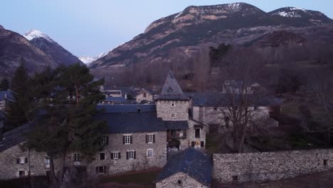 Sunset-hues-over-Anciles,-historic-Pyrenean-village,-nestled-amidst-Spanish-peaks-and-traditional-stone-houses---Aerial