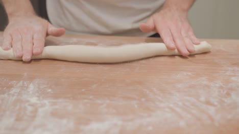 Hands-rolling-fresh-dough-for-baguette,-slow-motion