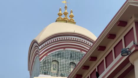 Low-angle-shot-of-gold-plated-peak-on-Kalighat-Temple-during-daytime-in-Kolkata,-India