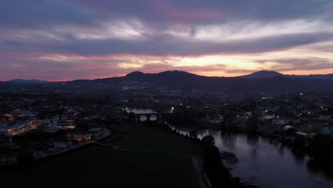 Tonos-Crepusculares-Sobre-Barcelos,-Con-El-Puente-Medieval-Que-Cruza-El-Río-Sereno,-Portugal---Aéreo