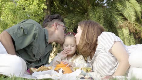 Una-Joven-Familia-Feliz-Haciendo-Un-Picnic-Con-Su-Alegre-Hija-En-El-Parque-De-La-Ciudad