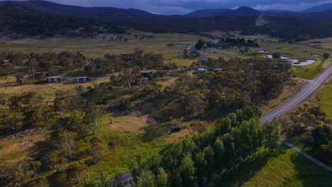 Luftaufnahme-Des-Crackenback-Alpine-Way-Highway-Mit-Bauernhöfen,-Häusern-Und-Wolkigen-Bergketten,-New-South-Wales,-Australien