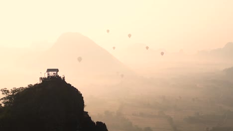 drone-shot-of-viewpoint-watching-hot-air-balloons-at-sunsrise-in-Vang-Vieng,-the-adventure-capital-of-Laos