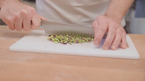 Close-up-of-hands-chopping-pistachios-on-a-cutting-board-in-slow-motion
