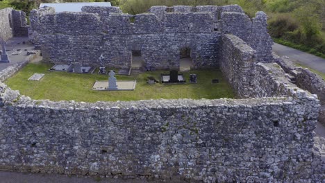 aerial-pullback-unveils-intricate-ruins,-expanding-to-encompass-Annaghdown-Abbey
