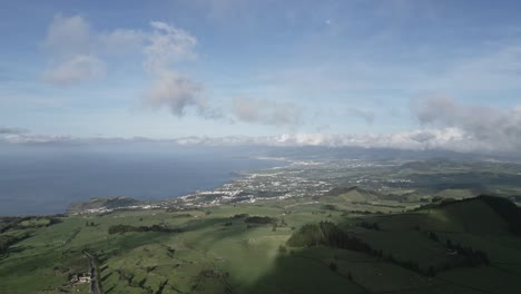 Pico-do-carvao,-sao-miguel,-lush-green-landscape-with-ocean-horizon,-cloudy-skies,-aerial-view