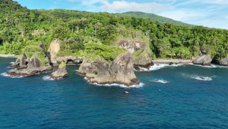 Batu-kapal-beach-on-weh-island,-showcasing-lush-greenery-and-rocky-coastline-under-clear-blue-skies,-aerial-view