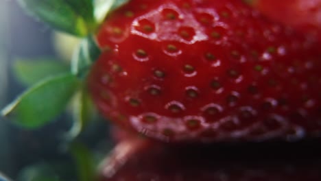 Macro-detailed-video-of-a-pile-of-strawberries,-red-strawberry,-green-leaf,-tiny-seeds,-on-a-rotating-reflection-stand,-smooth-movement