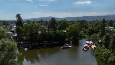 Vista-Aérea-De-Trajineras-Moviéndose-En-El-Lago-Xochimilco,-En-El-Soleado-México