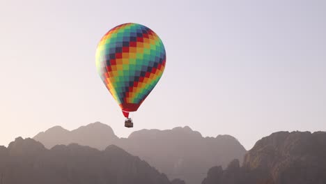 colorful-hot-air-ballon-floating-over-mountains-in-Vang-Vieng,-the-adventure-capital-of-Laos
