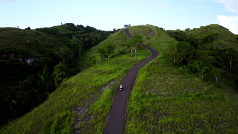 Scooter-Conduciendo-Cuesta-Arriba-En-Las-Colinas-De-Teletubbies-De-Nusa-Penida,-Bali.