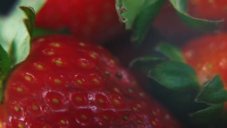 Macro-detailed-video-of-a-pile-of-strawberries,-red-strawberry,-green-fruit,-tiny-seeds,-on-a-rotating-stand,-smooth-movement