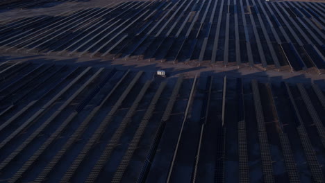 Aerial-View-of-Massive-Solar-Power-Plant,-Arrays-of-Solar-Panels-in-Twilight,-Revealing-Drone-Shot