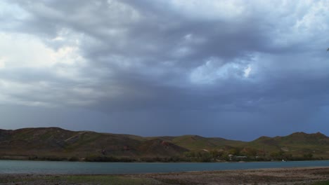 La-Fascinante-Transformación-En-Cámara-Rápida-De-Una-Tormenta-De-Verano,-Mientras-Ráfagas-De-Viento-Levantan-Remolinos-De-Polvo-A-Lo-Largo-Del-Río,-Creando-Una-Muestra-Cautivadora-Del-Poder-Y-La-Belleza-De-La-Naturaleza.