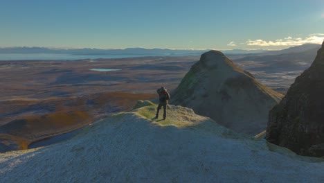 Caminante-De-Montaña-Parado-En-El-Borde-De-Un-Acantilado-Helado-Con-Vistas-Lejanas-Al-Horizonte-Montañoso-De-Invierno-Al-Amanecer